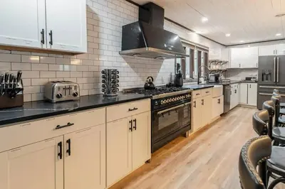 a kitchen with white cabinets and black counter tops at Poconos Pool Paradise in East Stroudsburg
