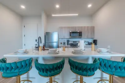 a kitchen with a large island with blue bar stools at Emerald Escape, Free Parking, 2 Bath, Sleeps 8 Near American Dream and The Airport, King Bed and 2 Queen Beds, Washer and Dryer in Orange