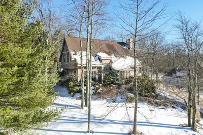 a house in the snow with trees in front of it at Wolf Hollow Harmony in Lake Harmony