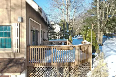 a house with a wooden porch in the snow at Wolf Hollow Harmony in Lake Harmony