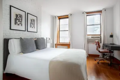 a bedroom with a white bed and a desk and windows at Nolita 2br w wd nr SoHo NYC-992 in New York