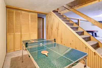 a ping pong table in a room with stairs at Pocono Vacation Rental with Game Room! in Tobyhanna