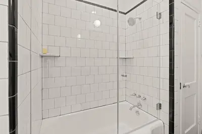 a white tiled shower with a glass shower backdoor at Stay Rafa At 2000 Spruce in Philadelphia