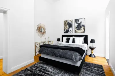 a bedroom with a black and white bed and a rug at Spacious studio in Brooklyn Heights in Brooklyn