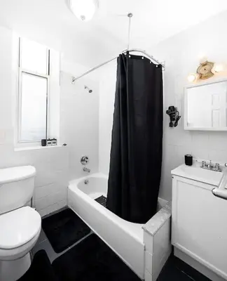 a bathroom with a toilet and a black shower curtain at Spacious studio in Brooklyn Heights in Brooklyn