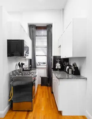 a kitchen with white cabinets and a stove top oven at Spacious studio in Brooklyn Heights in Brooklyn