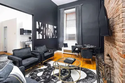 a living room with black furniture and a brick wall at Spacious studio in Brooklyn Heights in Brooklyn