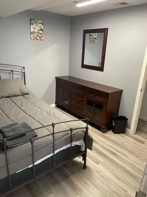 a bedroom with a bed and a dresser and a mirror at Modern one bedroom apartment in Princes Bay