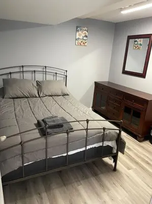 a bedroom with a bed and a wooden dresser at Modern one bedroom apartment in Princes Bay