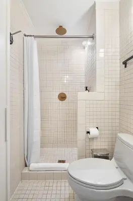 a white bathroom with a shower and a toilet at UNTITLED at 3 Freeman Alley in New York
