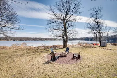 two benches sitting on a field next to a lake at Dock and Sunroom Waterfront Home Near Kalahari! in Pocono Summit