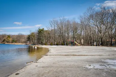 an empty beach with trees in the background and water at Dock and Sunroom Waterfront Home Near Kalahari! in Pocono Summit