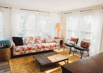 a living room with a couch and chairs and windows at Ode to the '70's creative private home with pool in Honey Brook