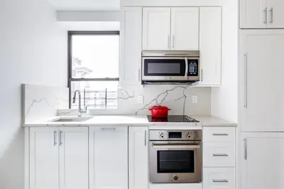 a white kitchen with a microwave and a sink at UWS 1BR w Gym Doorman nr Riverside Park NYC-511 in New York