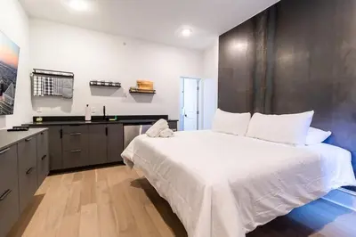 a bedroom with a large white bed and a kitchen at Thena Hotel- Lux Studio in Philadelphia