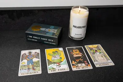 a candle and four cards next to a book and a candle at Thena Hotel- Lux Studio in Philadelphia