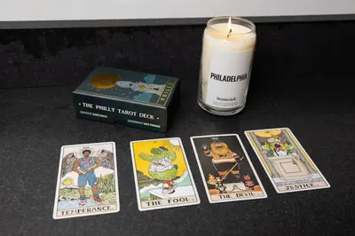 a candle and four cards next to a book and a box at Thena Hotel - Ground Floor 1 Bedroom Suite in Philadelphia