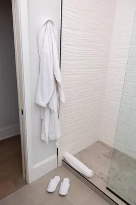 a bathroom with a shower with white towels and slippers at Thena Hotel - Oversized 1 Bedroom in Philadelphia