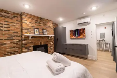 a bedroom with a brick wall and a bed and a fireplace at Thena Hotel - Oversized 1 Bedroom in Philadelphia