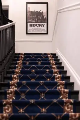 a staircase with a blue carpet and a picture on the wall at Thena Hotel - Oversized 1 Bedroom in Philadelphia