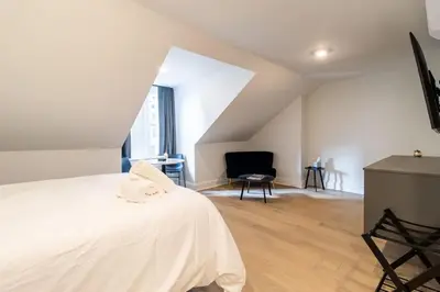 a bedroom with a white bed and a chair at Thena Hotel - Spacious Studio in Philadelphia