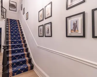 a hallway with a staircase with framed pictures on the wall at Thena Hotel - Spacious Studio in Philadelphia