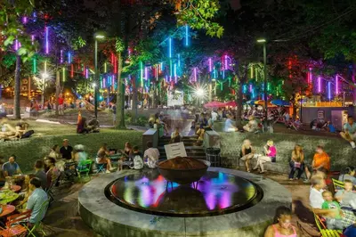 people sitting around a fountain in a park at night at Thena Hotel - Spacious 1 Bedroom - City Center in Philadelphia