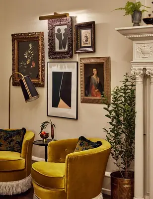 a living room with two chairs and paintings on the wall at Guild House Hotel in Philadelphia