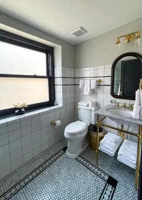 a bathroom with a toilet and a sink and a window at Guild House Hotel in Philadelphia