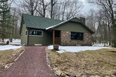 a small house with a gravel driveway in front of it at Woodland Cabin Retreat in Lake Harmony