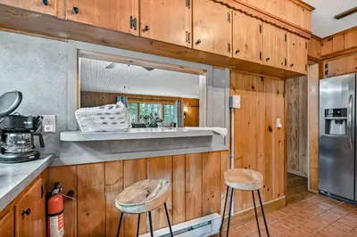 a kitchen with wooden walls and two stools in a kitchen at Woodland Cabin Retreat in Lake Harmony