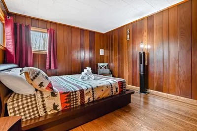 a bedroom with a bed in a room with wooden walls at Woodland Cabin Retreat in Lake Harmony