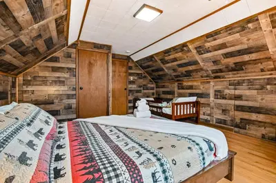 a bedroom with a bed in a room with wooden walls at Woodland Cabin Retreat in Lake Harmony
