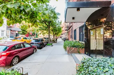 a red car parked on a sidewalk next to a street at W Village 1BR w Elevator WD nr subway NYC-762 in New York