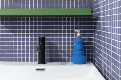 a blue tiled bathroom with a blue bottle on a sink at YOWIE Hotel in Philadelphia