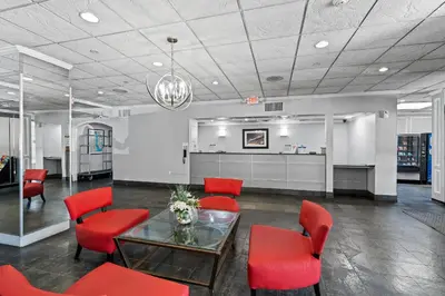 a waiting room with red chairs and a table at Executive Inn - Fort Lee in Fort Lee
