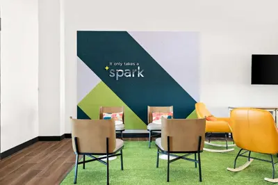 a waiting room with chairs and a wall with a splash at Spark by Hilton Lancaster Dutch Country in Lancaster