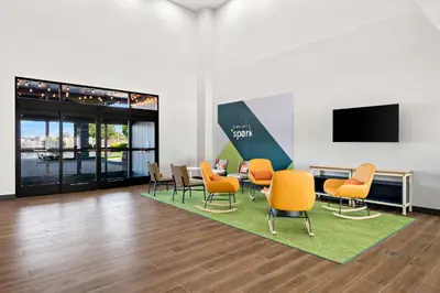 a waiting room with chairs and a table and a tv at Spark by Hilton Lancaster Dutch Country in Lancaster