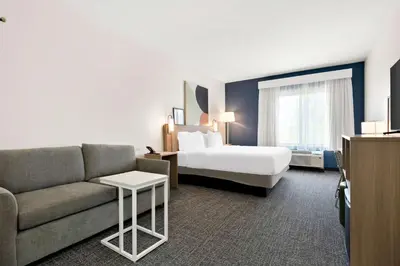 a hotel room with a bed and a couch at Spark by Hilton Lancaster Dutch Country in Lancaster