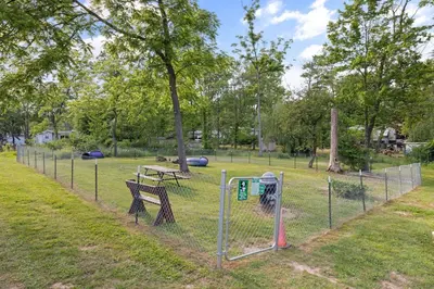 a fence with a bench and a picnic table in a park at Cozy Cabin Within Campground in Mifflinburg