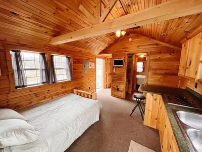 a bedroom in a log cabin with a bed and a sink at Deluxe Cabin Within Campground in Mifflinburg