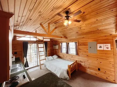 a bedroom with a bed in a wooden cabin at Deluxe Cabin Within Campground in Mifflinburg