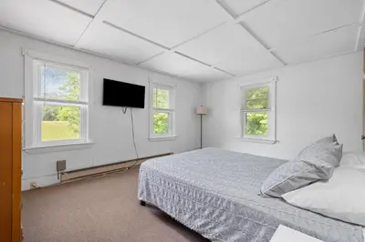 a white bedroom with a bed and two windows at Entire House within Campground in Mifflinburg