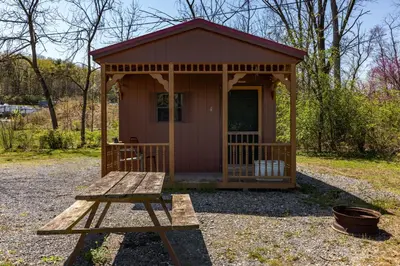 a small cabin with a bench in front of it at Cozy Cabin4 Within Campground in Mifflinburg