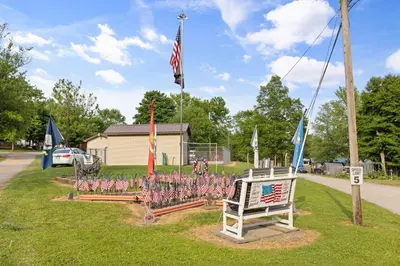 a park with flags and a bench with a sign at Deluxe Cabin7 Within Campground in Mifflinburg