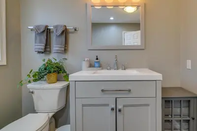 a bathroom with a toilet and a sink and a mirror at Lovely Poconos Cabin with Resort Amenities! in Gouldsboro