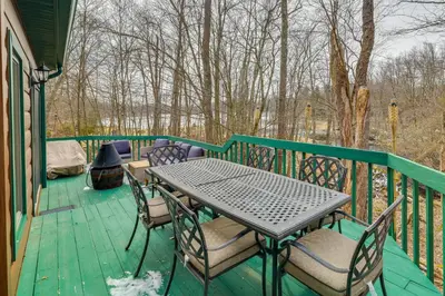 a table and chairs on a green deck at Lovely Poconos Cabin with Resort Amenities! in Gouldsboro