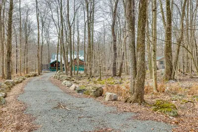 a dirt road leading to a house in the woods at Lovely Poconos Cabin with Resort Amenities! in Gouldsboro