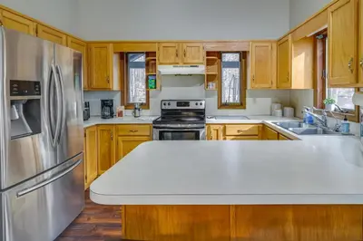 a kitchen with wooden cabinets and a stainless steel refrigerator at Lovely Poconos Cabin with Resort Amenities! in Gouldsboro