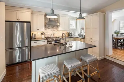 a kitchen with a stainless steel refrigerator and bar stools at Brooke House In The Heart of Downtown with Patio! in Lambertville